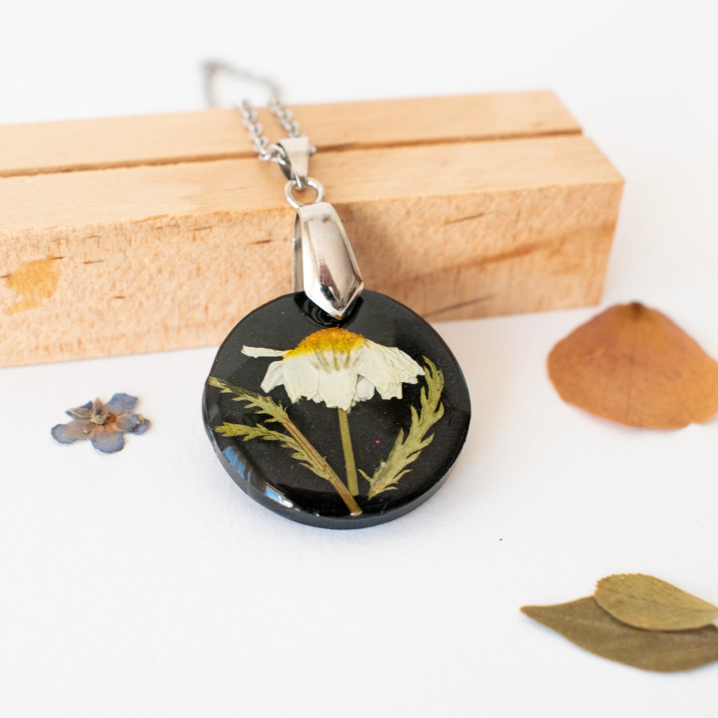 colgante negro con flor de manzanilla